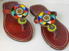 Elevate your summer style with our stunning Maasai Beaded Leather Sandals, expertly handcrafted in Kenya. Each pair features vibrant, intricate beadwork inspired by traditional Maasai designs, making every sandal a unique piece of art.  Made from high-quality leather, these sandals offer durability and comfort for all-day wear. Perfect for both casual outings and special occasions, they not only showcase beautiful craftsmanship but also support local artisans. Step into a world of color and cult Traditional Beaded Brown Flip Flops, Traditional Brown Beaded Flip Flops, Traditional Handmade Brown Flip Flops, Traditional Beaded Flip Flops With Round Toe, Traditional Beaded Flip Flops For Festivals, Traditional Multicolor Beaded Flip Flops, Traditional Brown Beaded Sandals, Traditional Adjustable Brown Flip Flops, Traditional Toe Loop Flip Flops For Vacation