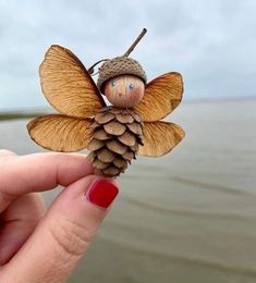 a hand holding a tiny pine cone fairy figurine