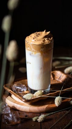 there is a drink with whipped cream in it on the wooden table next to flowers