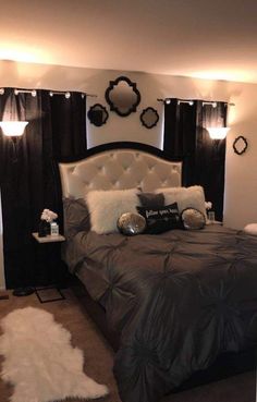 a bedroom with black and white bedding, pillows and lights on the headboard