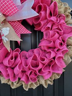 a pink wreath with burlocks and bows on the front door