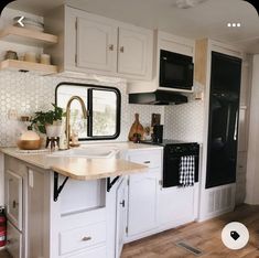 a kitchen with white cabinets and black appliances in the back wall, along with wooden flooring