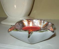 a candle that is sitting on a table next to a white cup and saucer