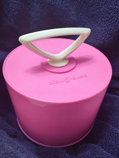 a pink container with a white handle on it's lid sitting on a blue blanket