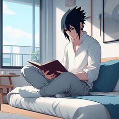 a man sitting on top of a bed reading a book in front of a window