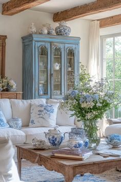 Sunlit French country living room featuring antique wooden tables, blue accents, and porcelain pieces Cotton Blue Cottage, Blue And Green French Country Decor, Light Blue Furniture Living Room, Blue And White Farmhouse Decor, Victorian Blue Aesthetic, Blue White Green Living Room, Romantic Country Decor, Blue Vintage Living Room, Vintage Blue Living Room