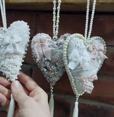 three heart shaped brooches are being held by someone's hand in front of a brick wall