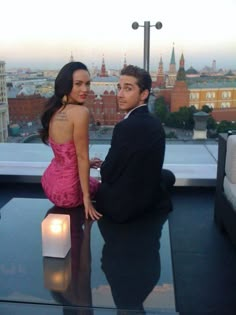 a man standing next to a woman on top of a building