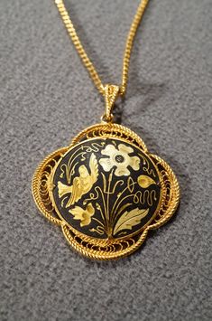 I am offering this fabulous vintage yellow gold tone necklace. This piece is truly gorgeous, and it has the following features: * beautiful vintage necklace * yellow gold tone * jet black enameled * flower design * pendant measuring 1.5 inches in diameter * 19 inches in length This is a fantastic and classic piece. There is tons of sparkle and shine with this piece. It will beautifully complement your upcoming fashion season. Buyer pays all shipping and handling. Gold Enamel Medallion Necklace, Gold Enamel Round Pendant Necklace, Collectible Yellow Gold Filigree Necklaces, Antique Gold Necklaces With Black Enamel, Yellow Gold Filigree Necklaces, Gold Enamel Flower Pendant Necklace, Gold Round Necklace With Black Enamel, Gold Engraved Necklaces For Evening, Gold Engraved Necklace For Evening