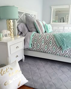 a white bed sitting in a bedroom next to a dresser and mirror on top of it