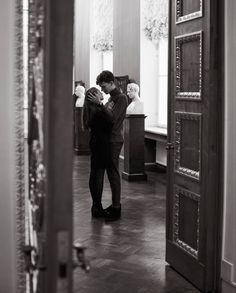 two people are standing in the hallway with their heads close to each other as they kiss