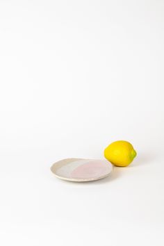 a white plate with a lemon on it next to a pink and white plate that has a yellow lemon on it