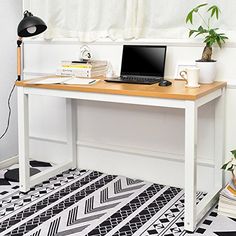 a laptop computer sitting on top of a wooden desk next to a potted plant