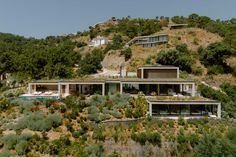 the house is on top of a hill with lots of trees and bushes around it