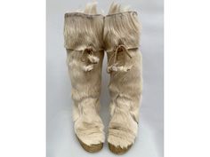 a pair of furry boots with bows on the side and fur around the ankles, all in beige