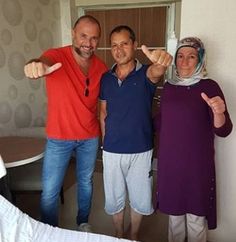 two men and a woman posing for the camera with their thumbs up in front of them