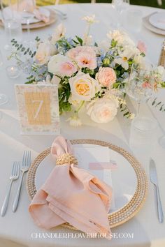 the table is set with pink napkins and silverware