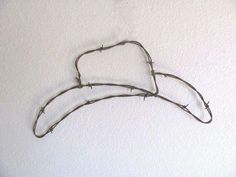 barbed wire hanging on the wall in front of a white wall with two hearts shaped like branches