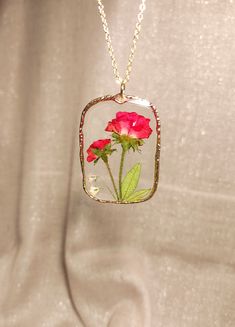 a red flower in a square glass pendant