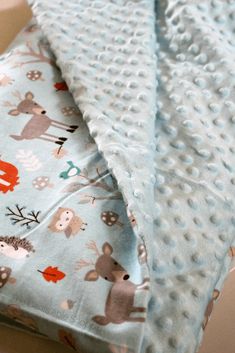 two baby blankets sitting next to each other on top of a table with an animal print