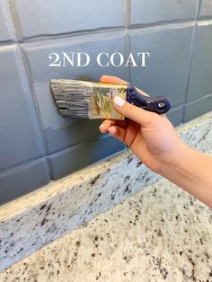 a hand holding a paint brush over a wall with the words 2nd coat on it