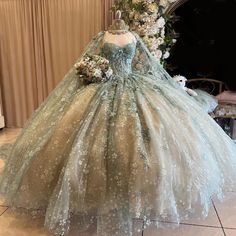 a dress on display in front of a mirror with flowers and greenery around it