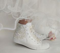 a pair of white shoes with flowers on the bottom and lace around the soles