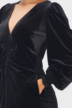 a woman is wearing a black dress with long sleeves and a cutout at the back