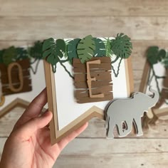 someone is holding up a card with an elephant and tree cut out of it's sides