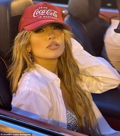 a woman wearing a coca cola hat sitting in a car