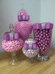 there are many candy in the glass vases on the table and one is pink