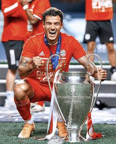 a man kneeling down next to a soccer trophy