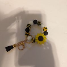 a yellow and black beaded bracelet with a sunflower charm on it's side