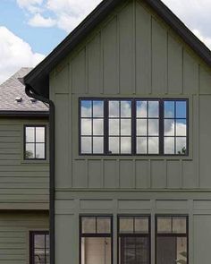 the front of a house with windows on each side and two cars parked in front