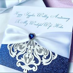 a blue and white wedding card with a diamond brooch