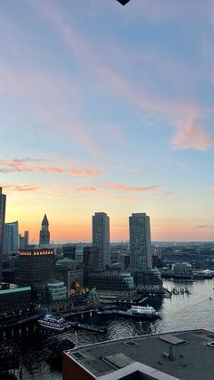 the city skyline is lit up at sunset with pink clouds in the sky and water below