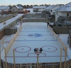 an outdoor ice rink in the middle of winter with snow on the ground and fence around it