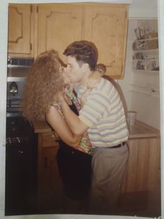 a man and woman kissing in the kitchen