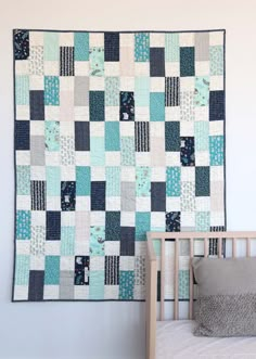 a baby crib with a blue and white quilt hanging on it's wall