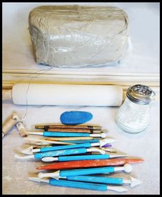 there are many different colored toothbrushes on the floor next to a jar and brush