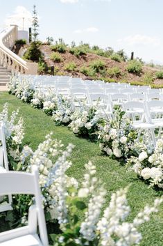 rows of white chairs lined up on the grass at a wedding ceremony with flowers and greenery