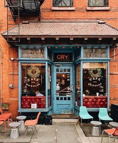 an old brick building with chairs and tables in front of it on the sidewalk outside