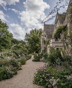 an old stone house surrounded by flowers and trees