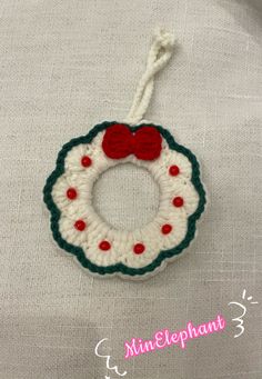 a crocheted christmas ornament with a red bow hanging from it's side