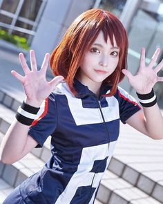 a woman with red hair is posing in front of some steps and holding her hands up