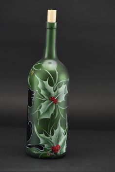 a green glass bottle decorated with holly leaves