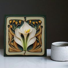 a white flower sitting on top of a table next to a cup