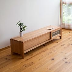 a wooden table with a potted plant sitting on it's shelf next to a window