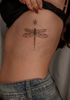 a woman's stomach with a dragonfly tattoo on it