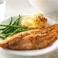 a white plate topped with fish and green beans next to potatoes, mashed potatoes and broccoli